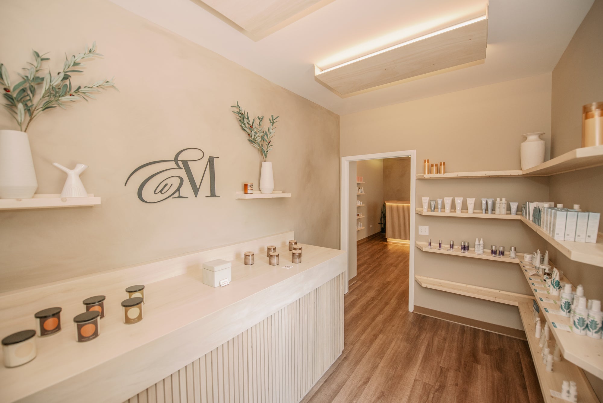Esthetics With Me studio in McHenry, IL, with the monogram feature wall and shelves of professional skincare