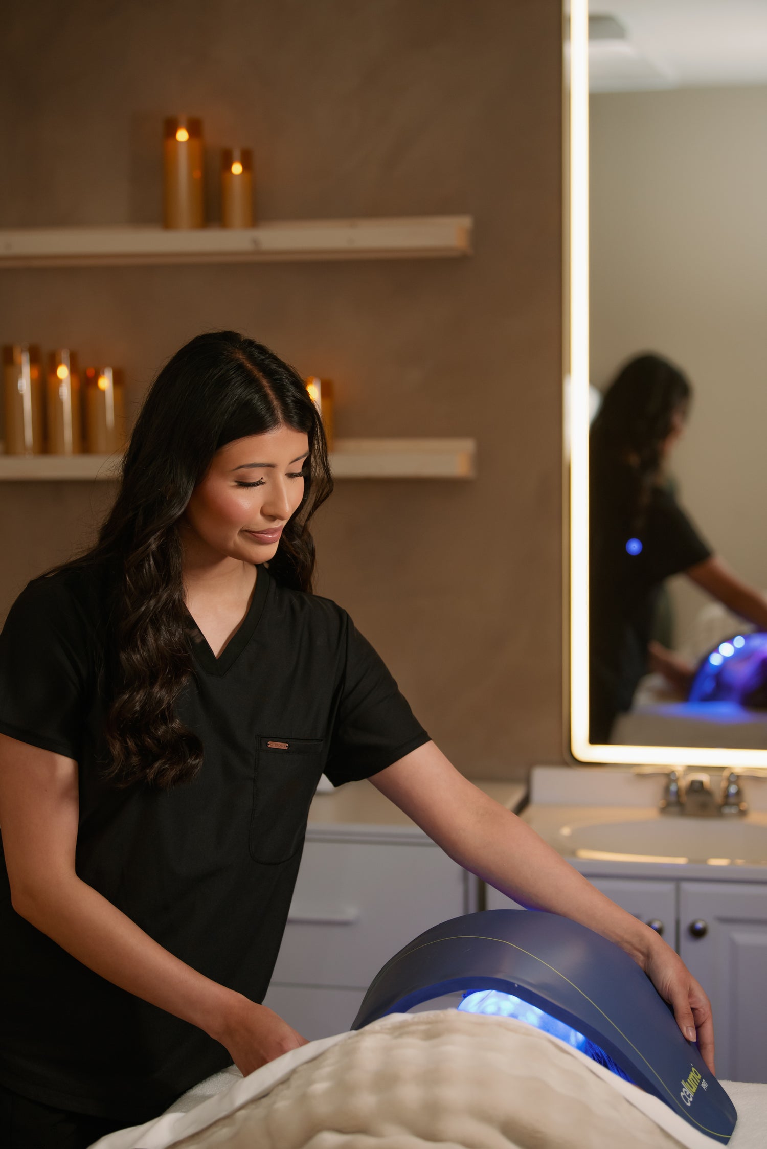 Esthetician positioning a blue LED light therapy mask over a client's face