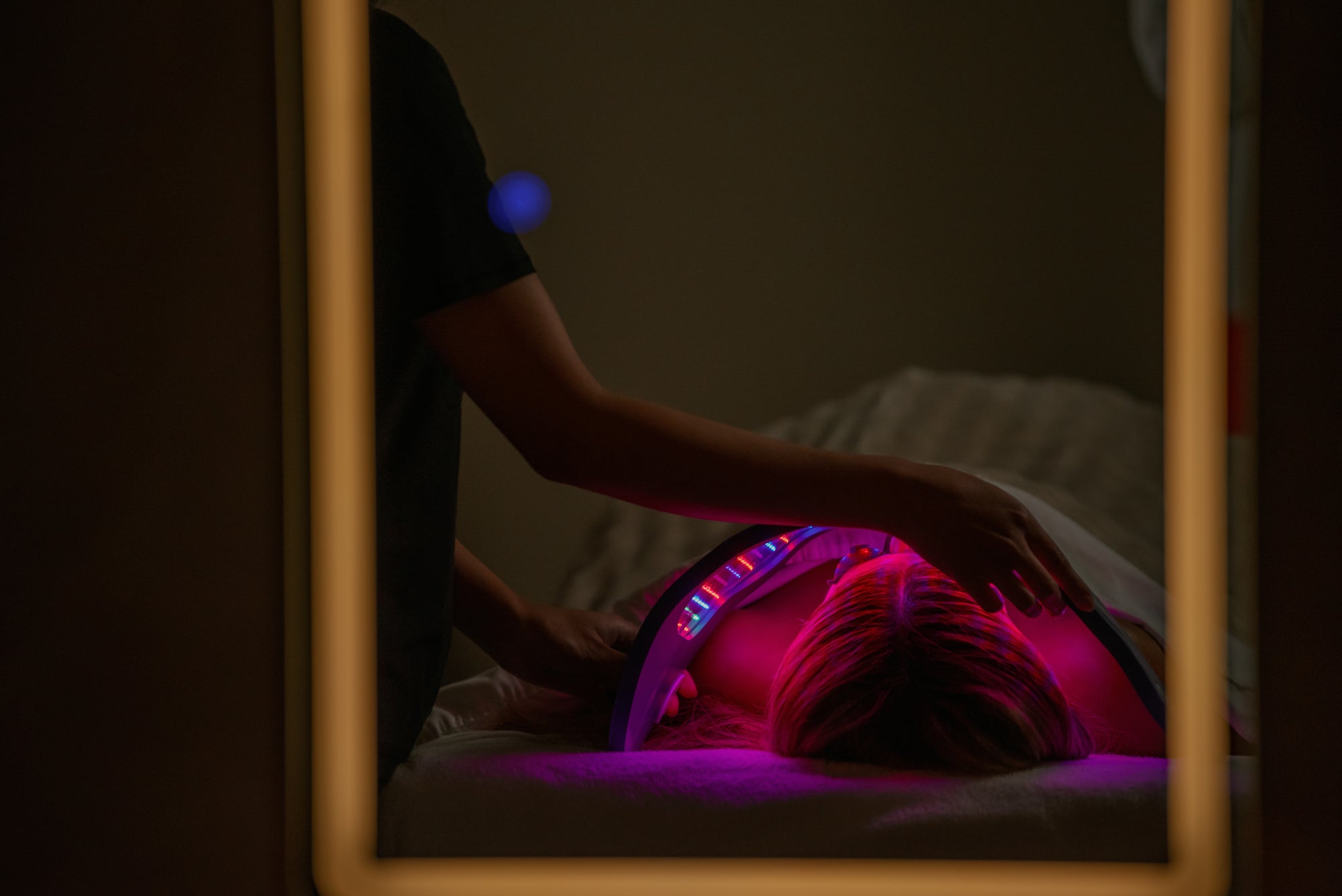 Red light therapy session reflected in the arched mirror of the treatment room