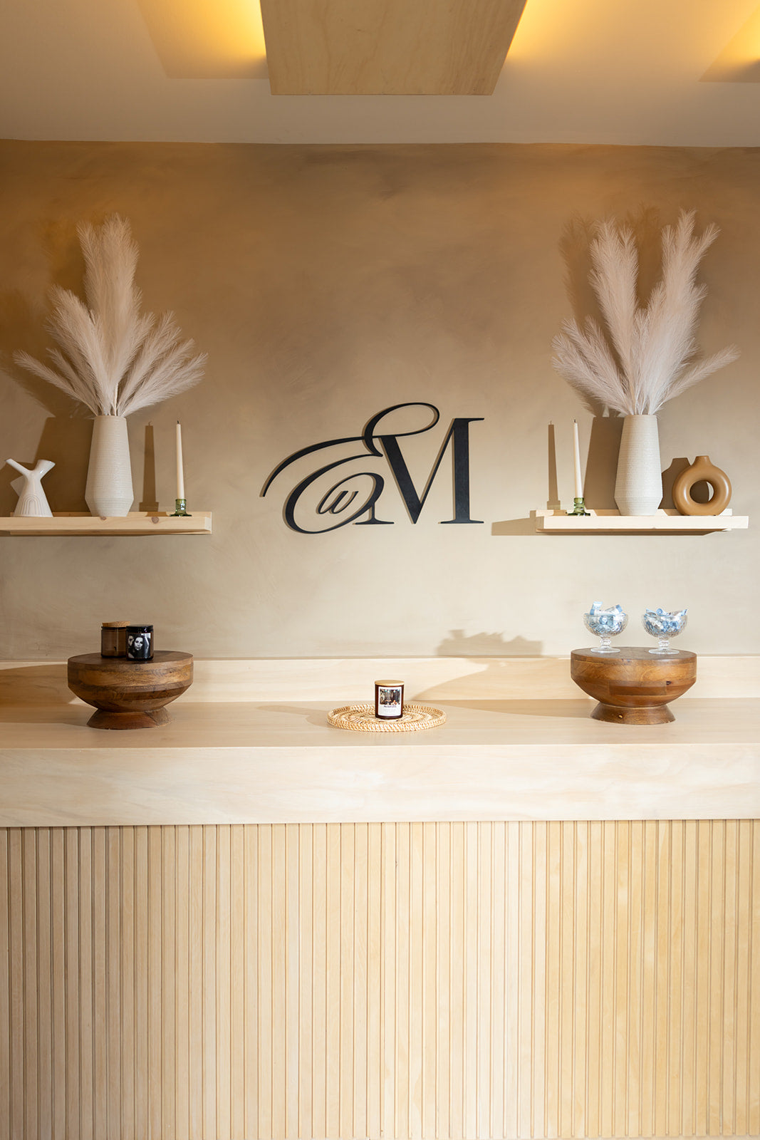 Esthetics With Me logo monogram wall behind the spa's front counter