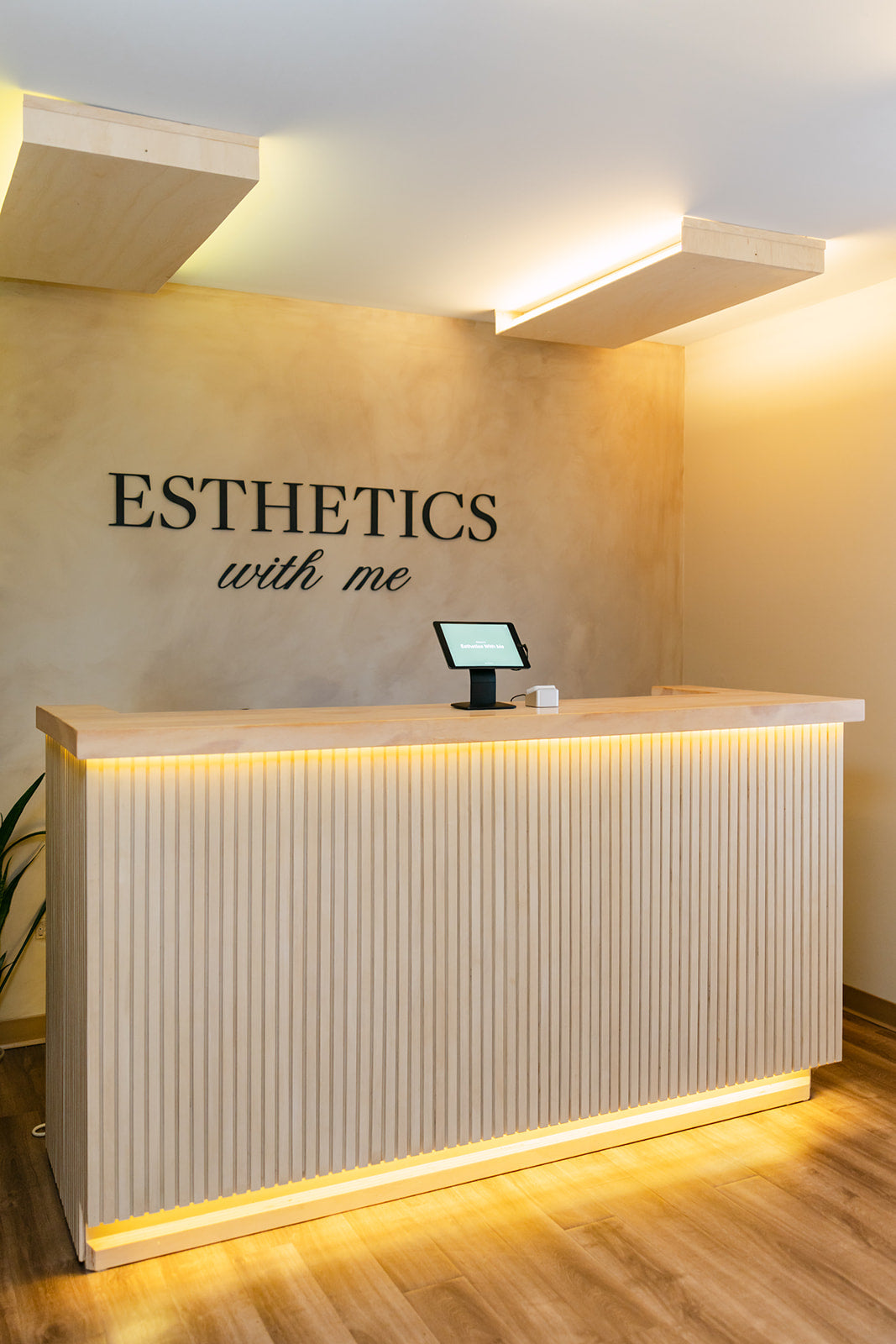 Lighted reception desk beneath the Esthetics With Me sign in the McHenry, IL spa