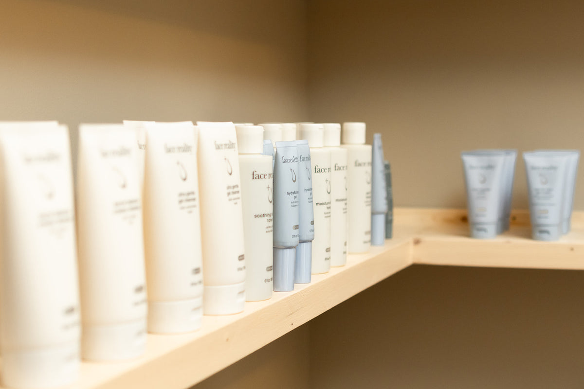Face Reality acne-safe skincare products lined up on a light wood shelf in the studio